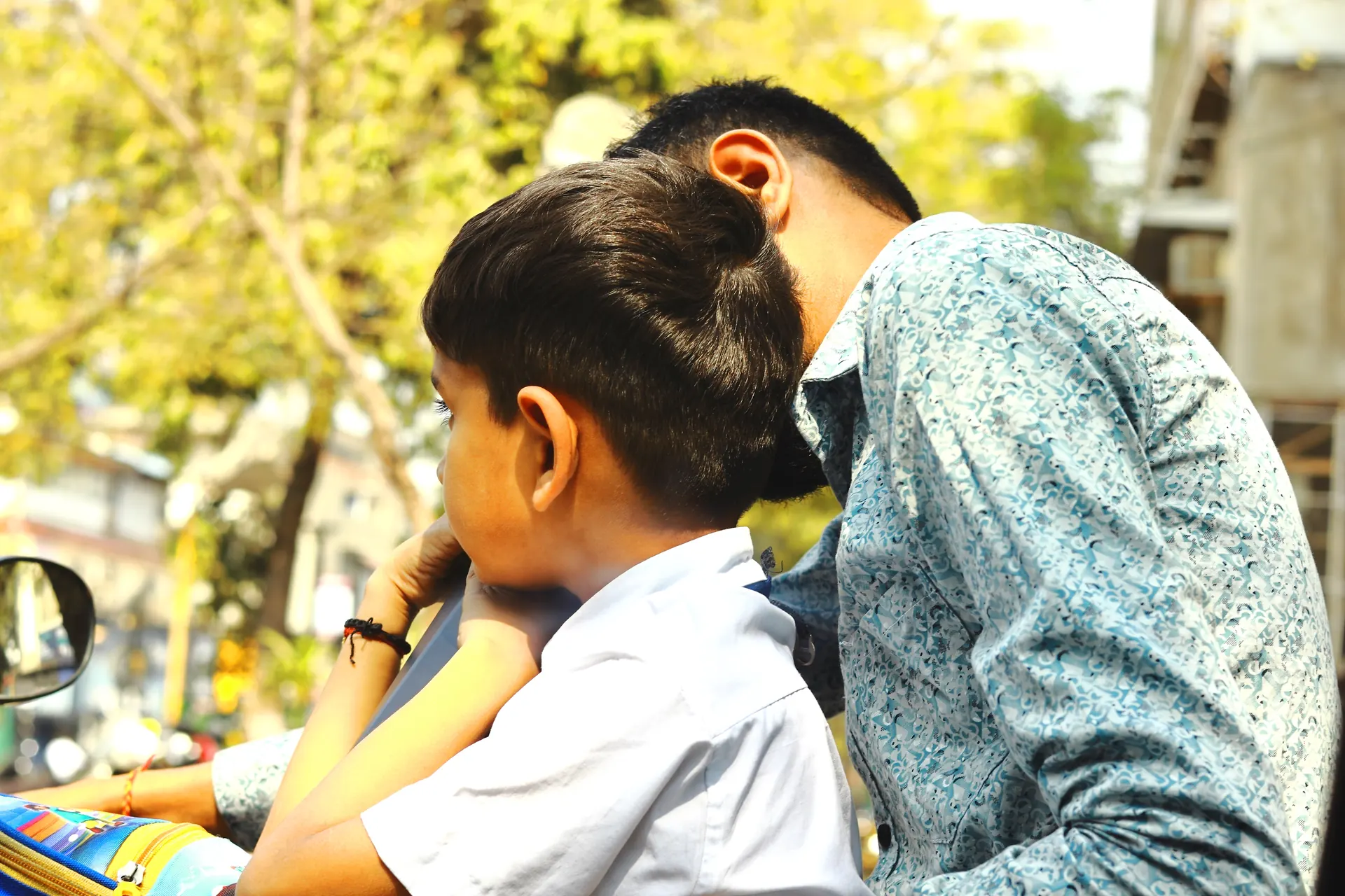 A father and son on a scooter in traffic, India