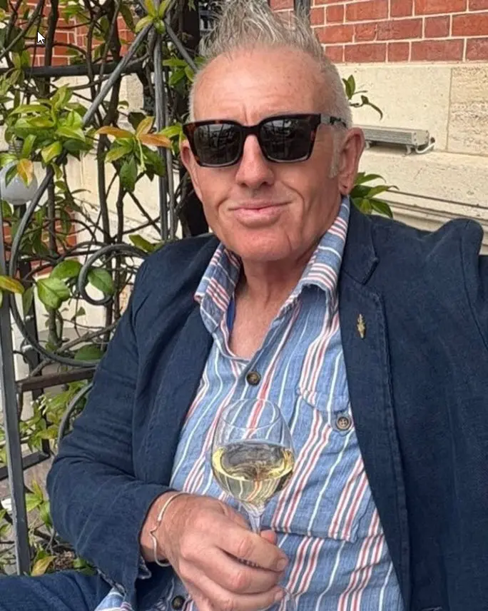 Telford Vice with a glass of wine, ivy-covered wall behind him