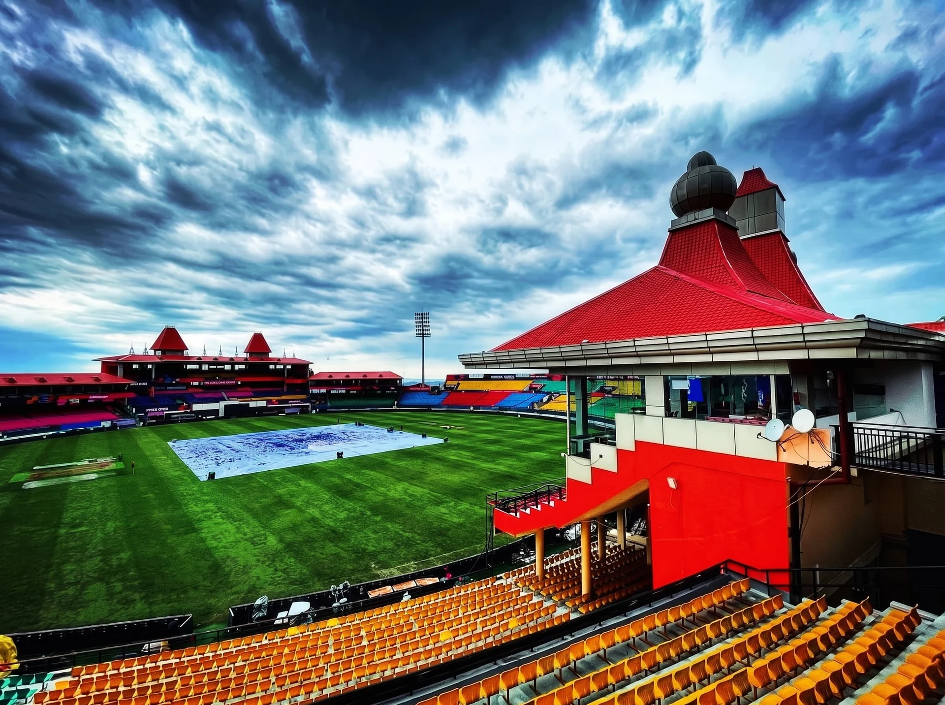 The red pagoda roofs of the HPCA Stadium, Dharamsala, under a stormy sky